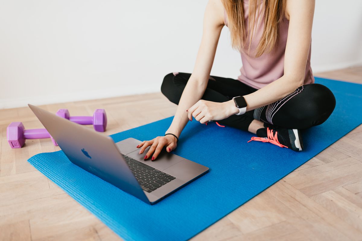 Placeholder: woman on a yoga mat at home with a laptop